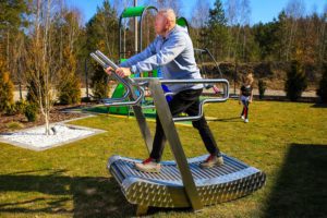 An elderly man exercises on an outdoor treadmill