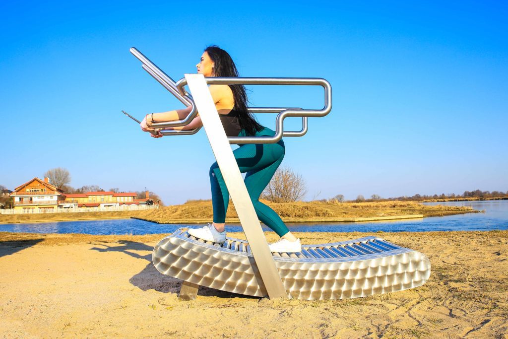 a woman exercises on the iGreenMill outdoor treadmill by the water