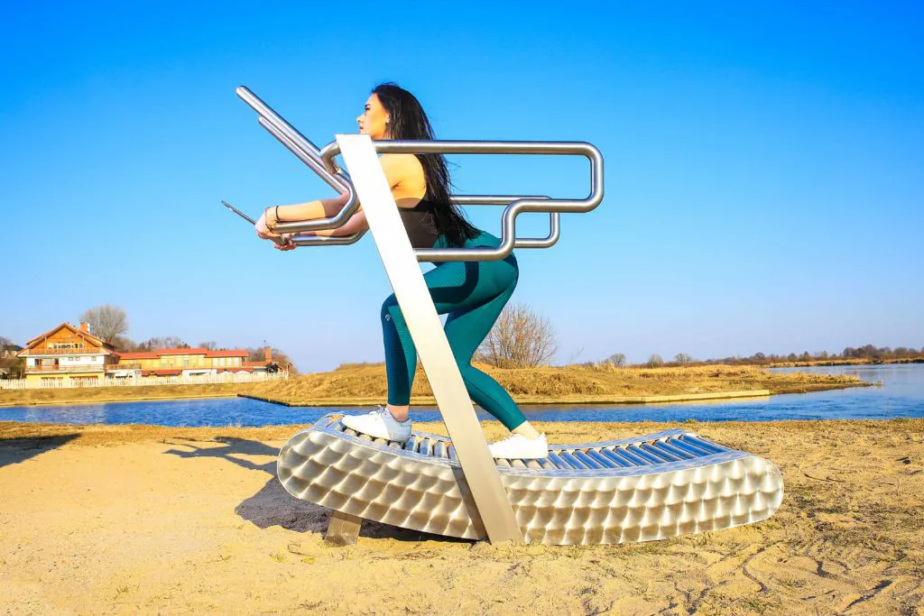 a woman exercises on the iGreenMill outdoor treadmill by the water