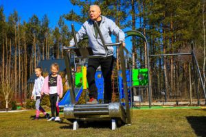 An elderly man exercises on an outdoor treadmill, third image
