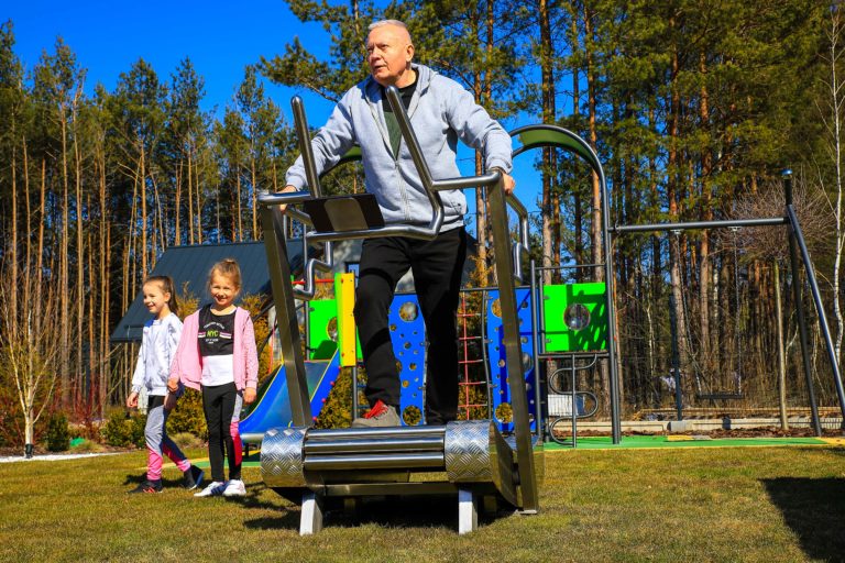 An elderly man exercises on an outdoor treadmill, third image