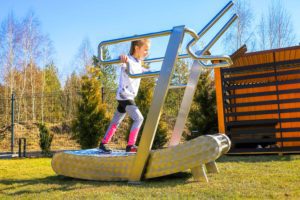a little girl walks on the GreenMill outdoor treadmill
