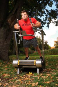 A muscular guy practices simple push-ups on the GreenMill City outdoor treadmill
