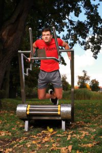 A muscular guy practices dips on the iGreenMill City outdoor treadmill