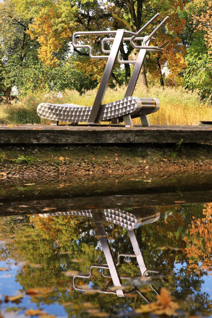 The iGreenMill City outdoor treadmill stands on a footbridge in the park, second image