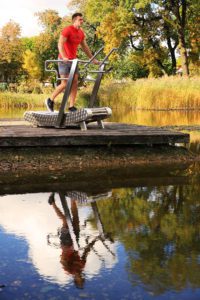 A man practices walking on the GreenMill City outdoor treadmill in the park, on a footbridge