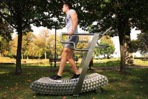 A man practices walking backwards on the GreenMill City outdoor treadmill in the park